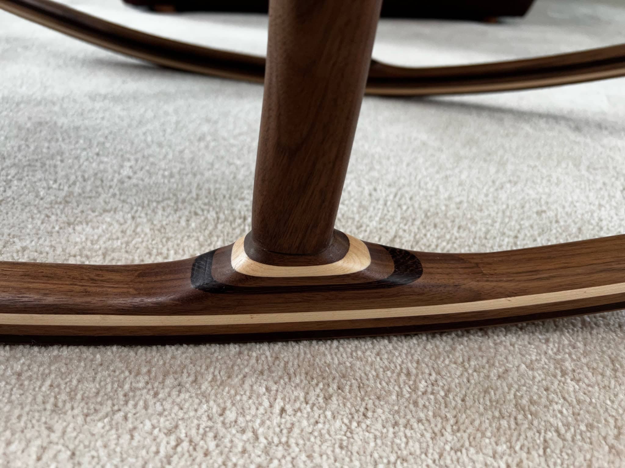 The rocker-to-leg joint, with a contrasting maple strip laminated into the walnut rocker.