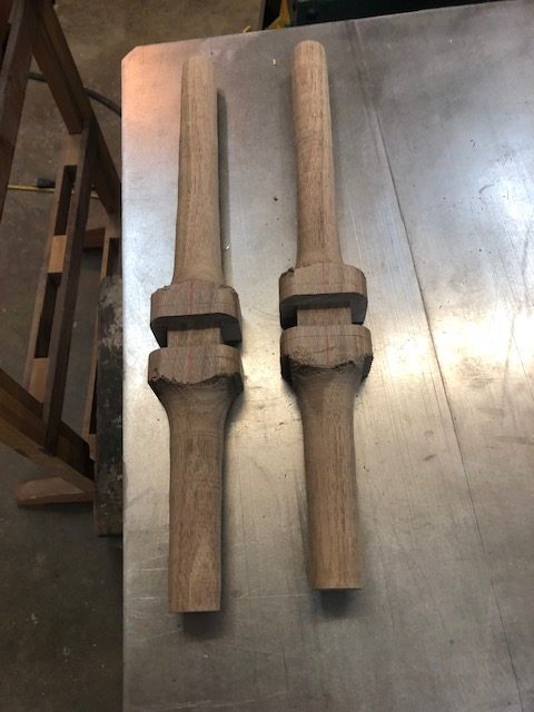 Two leg blanks after shaping, with the joinery cut where they meet the seat.