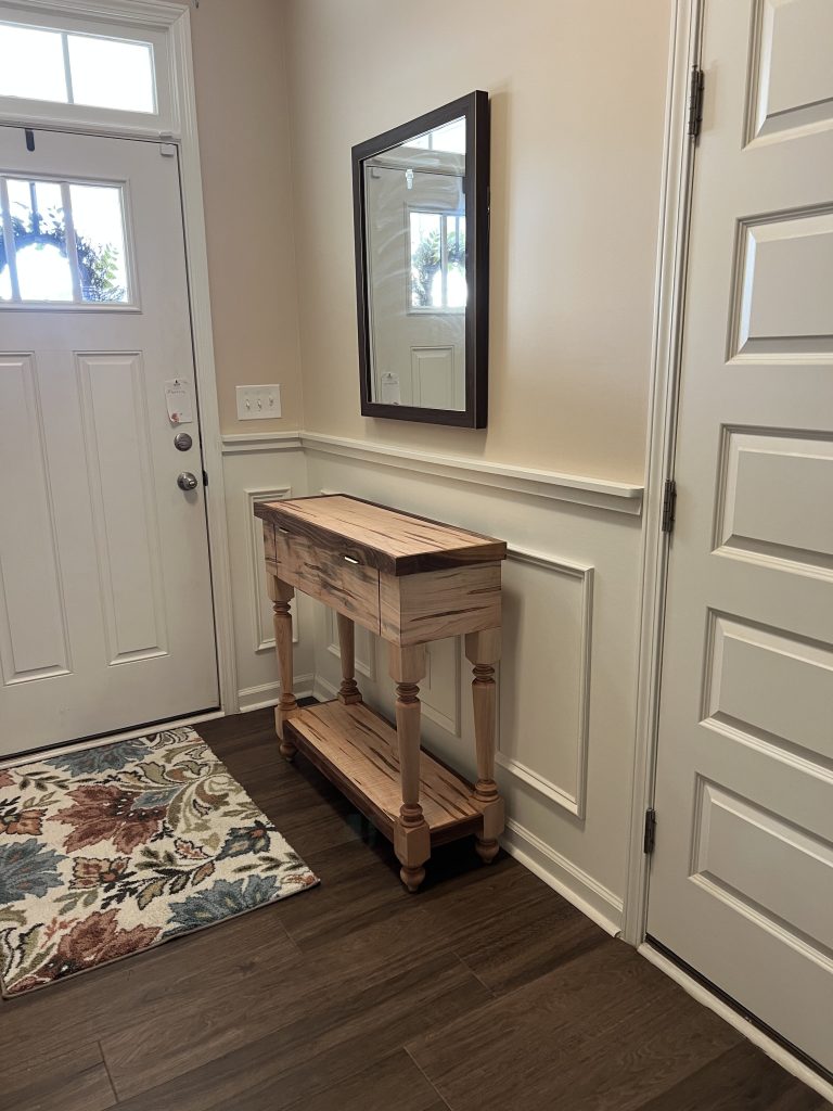 The finished table in its "final resting place" by the front door, ambrosia maple with walnut trim along the top edge and lower shelf.