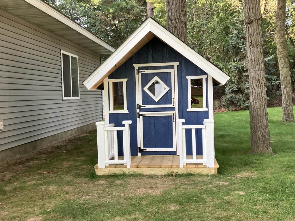 Straight-on front view of the navy siding, white trim, Dutch-style door with its diamond window and the two side windows.