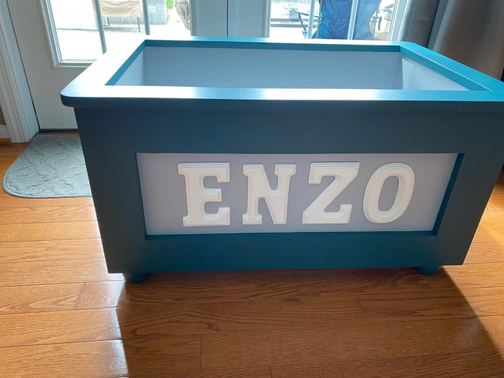"ENZO" in a deeper teal with a white panel, shown without the lid so the painted interior is visible.