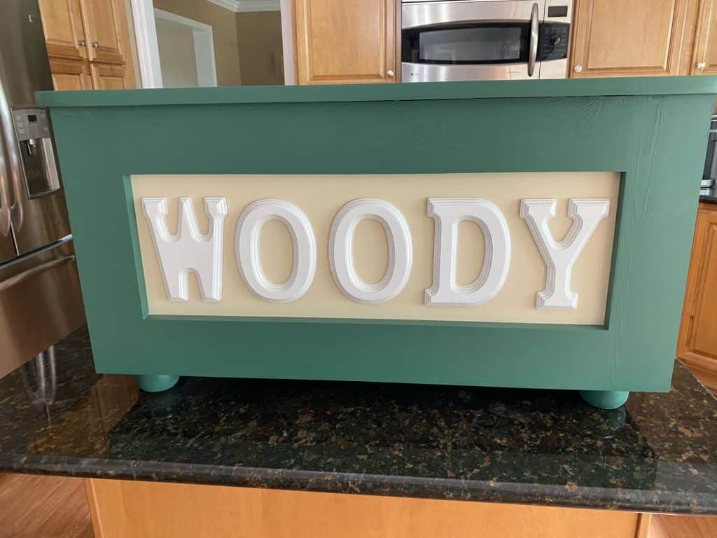 "WOODY" in green with a cream panel and white letters, sitting on the kitchen island.