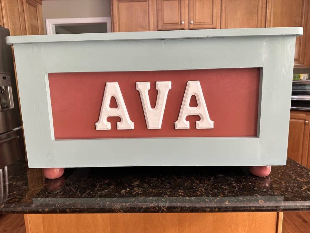 "AVA" in sage green with a rose panel, matching rose feet and pale pink letters.