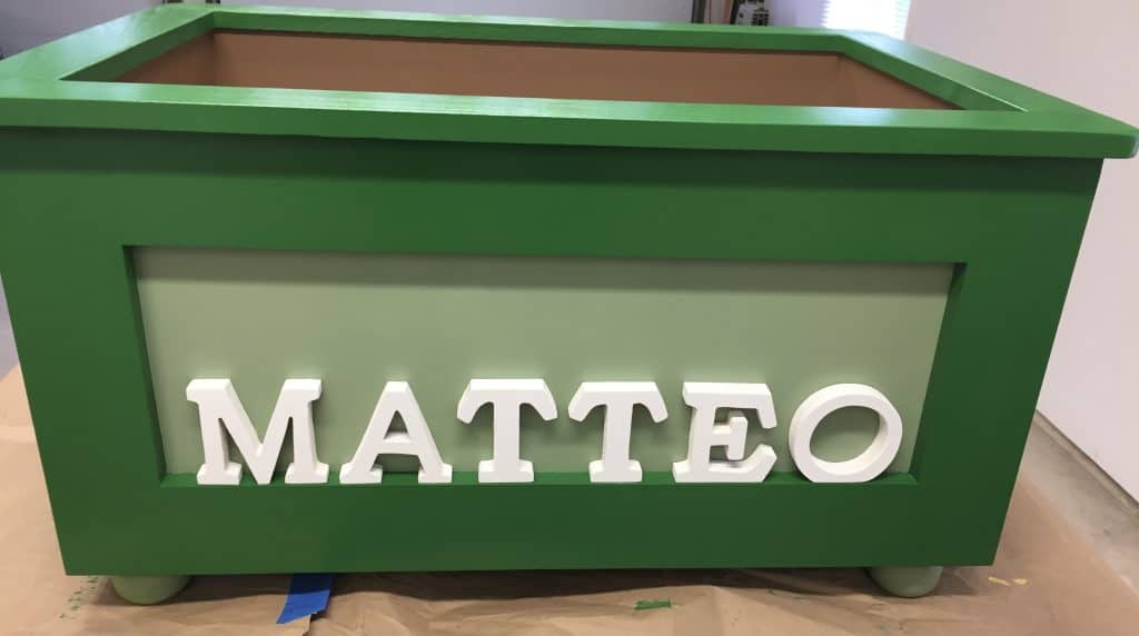 "MATTEO" in green and light green, photographed lid-off on a drop cloth with the painter's tape still on a foot.