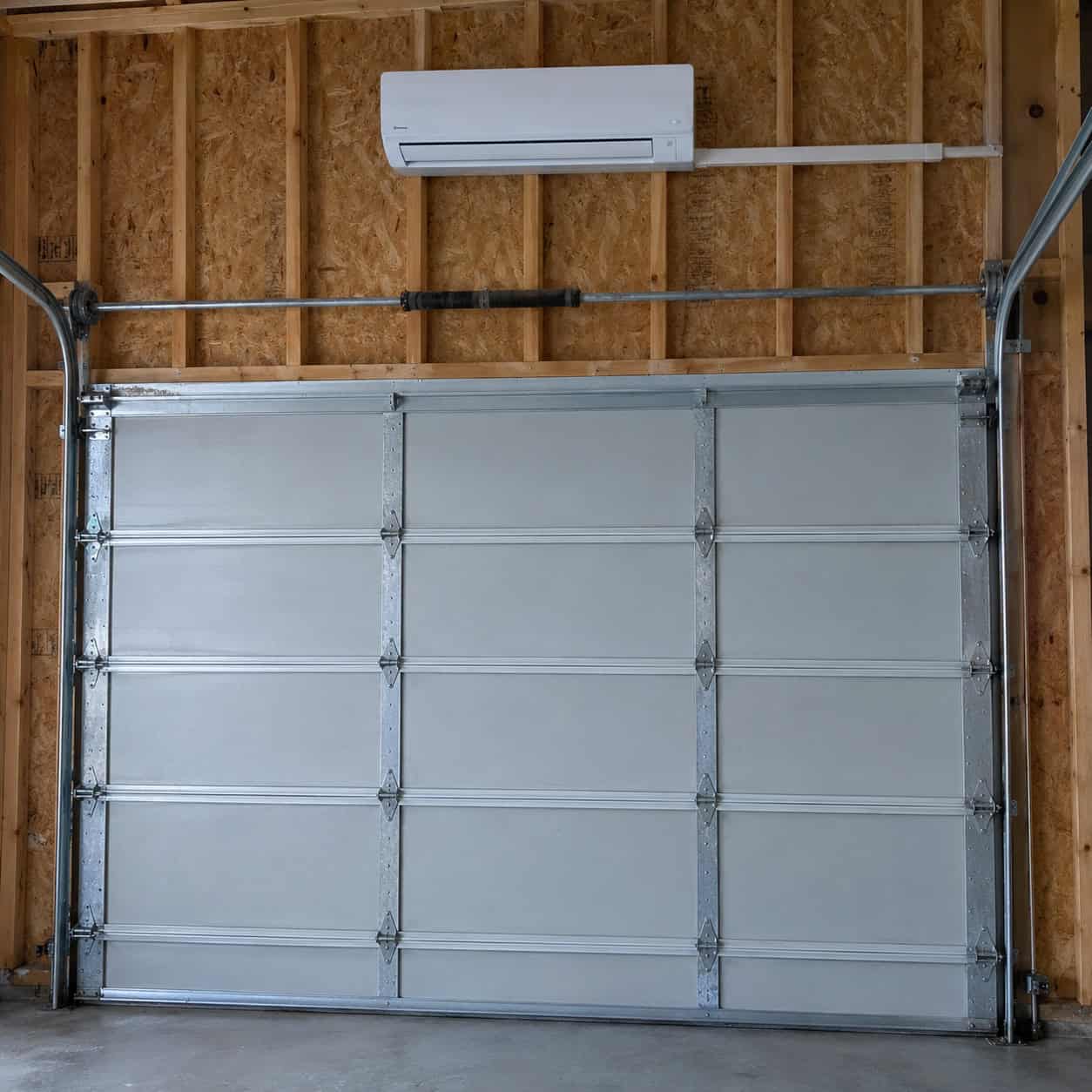 A mini split bolted to an uninsulated garage