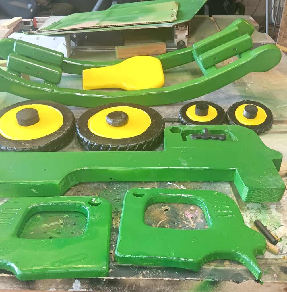 Painted parts laid out before assembly — rockers, seat, four wheels with Dremel-carved tread, the frame and the two motor enclosure sides.