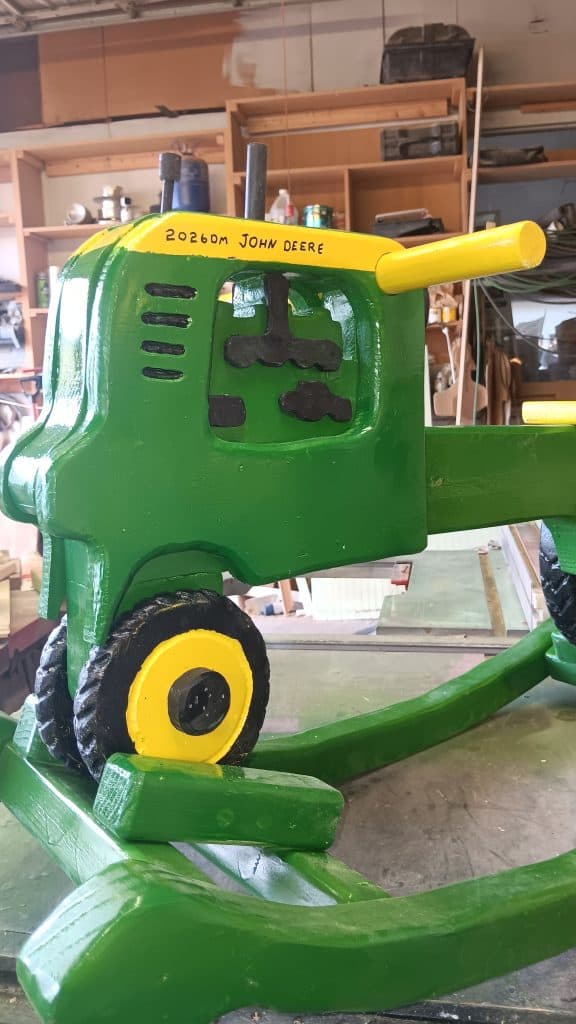 Front three-quarter view showing the fiberboard engine details, louvers and the yellow dowel handlebar.