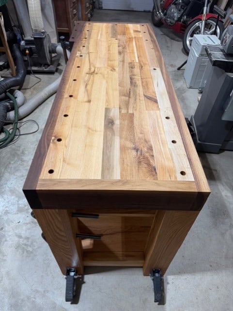 Looking down the repurposed maple top with its walnut edging and rows of dog holes.
