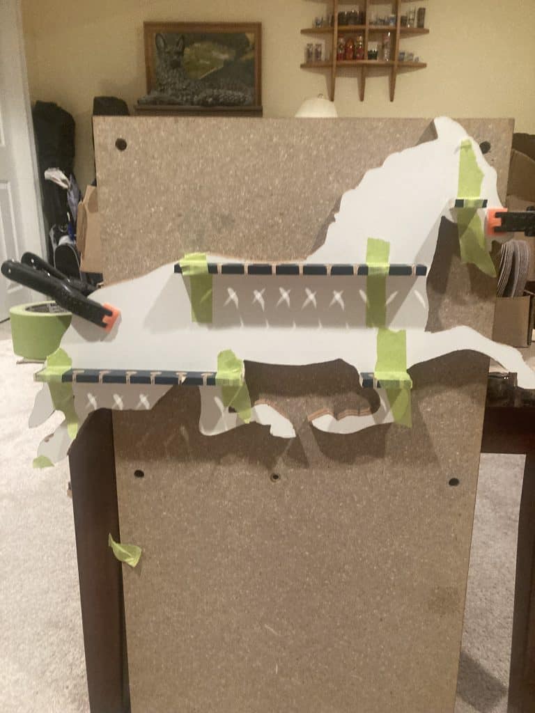 The cut-out horse clamped and taped to a work surface while the spoon rails are glued and held in place.