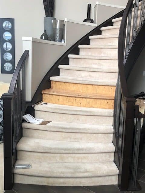 The starting point: carpeted curved stairs with the covering pulled back on two treads.
