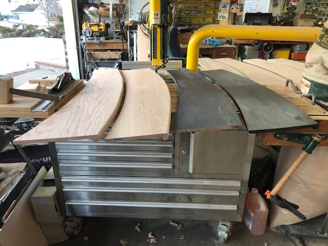 Curved treads at various stages lined up on the tool chest, some bare and some already stained.
