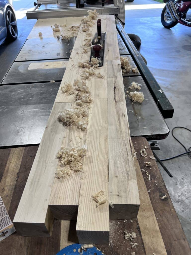 Hand planing the maple strips on the table saw, with shavings everywhere.